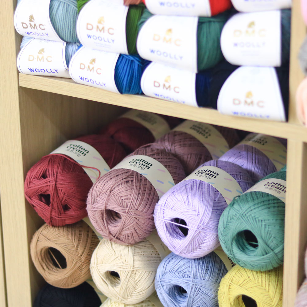 木製貨架上陳列著多種顏色的YARN-A Cotton Cream毛線，色彩柔和。