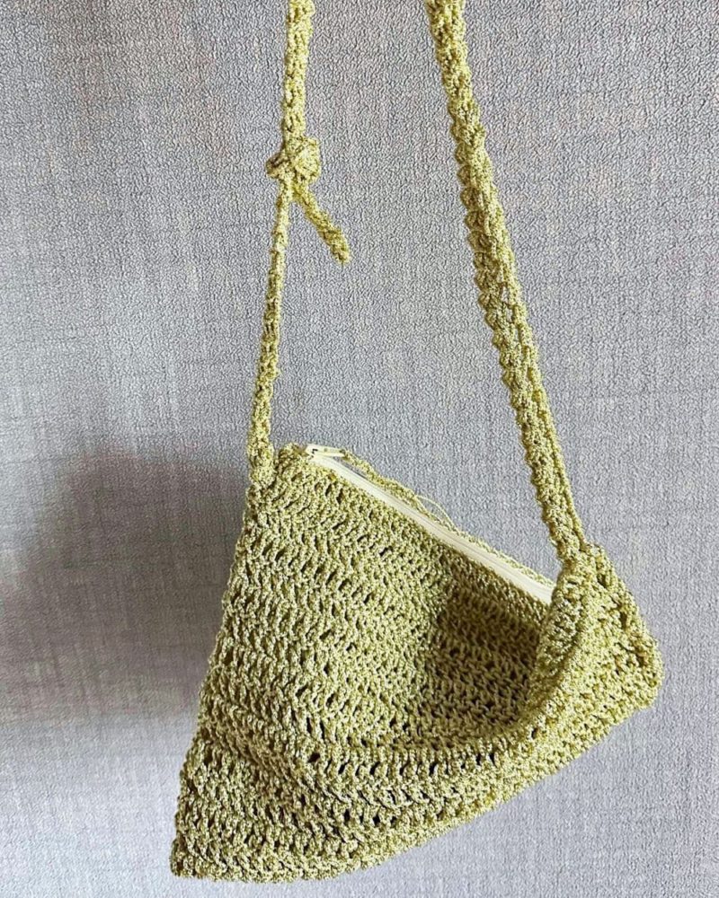 一個由淡金色金屬線鉤織的三角扭扭包，是織友Kiki Wong的作品，包包有拉鍊和可調節長度的背帶。