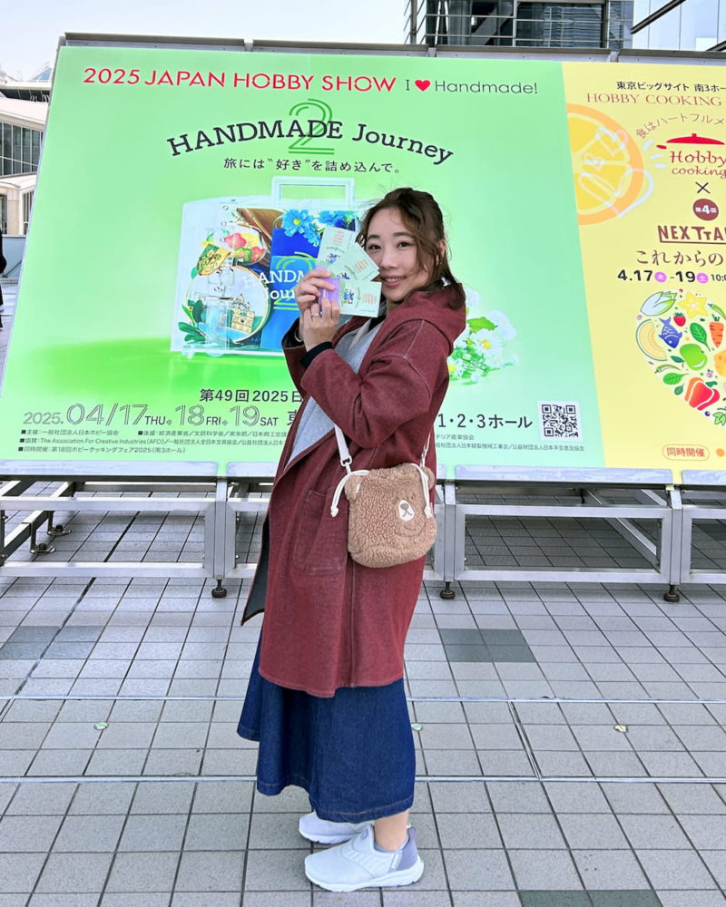 唧唧在2025日本Hobby Show展覽會場門口手持HAMANAKA贊助門票留影