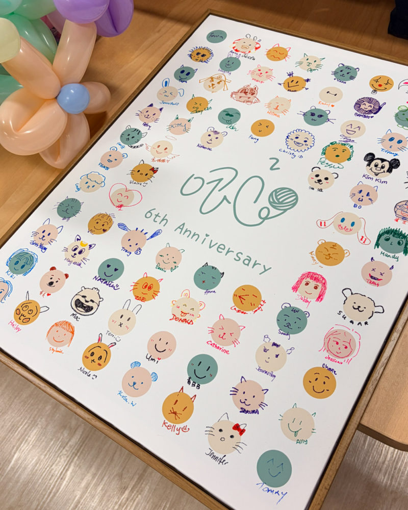 一張印有「zik2 6th Anniversary」標誌的白色簽到畫板，上面畫滿了數十個由參與活動的同學們親手繪製的可愛動物、人物頭像與塗鴉，色彩繽紛且充滿童趣。